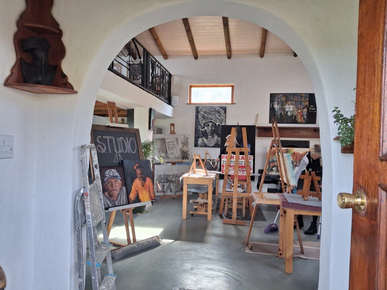 Arched doorway into the studio, easels and a chalkboard reading Studio inside