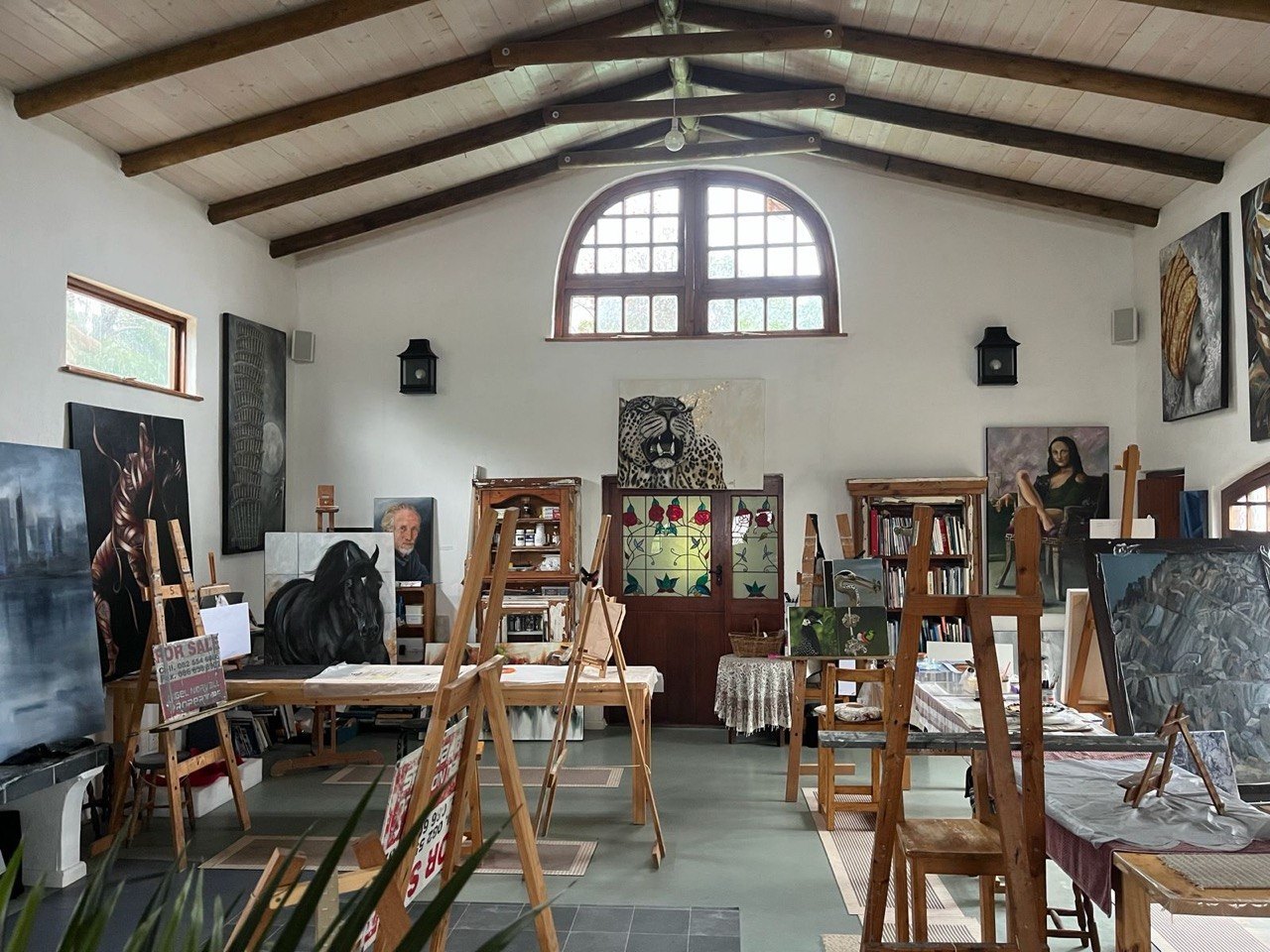 The main studio room at Cobwebs with rows of wooden easels and an arched window