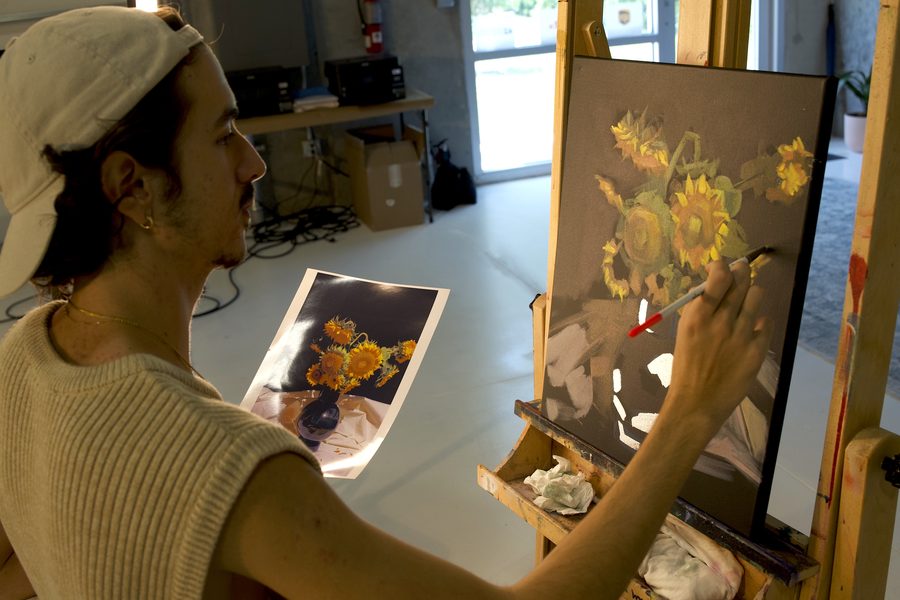 Student painting bright florals on a canvas at an easel