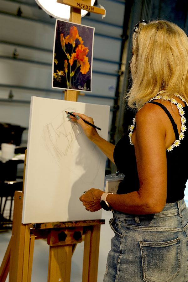 Student sketching florals at an easel in a bright studio