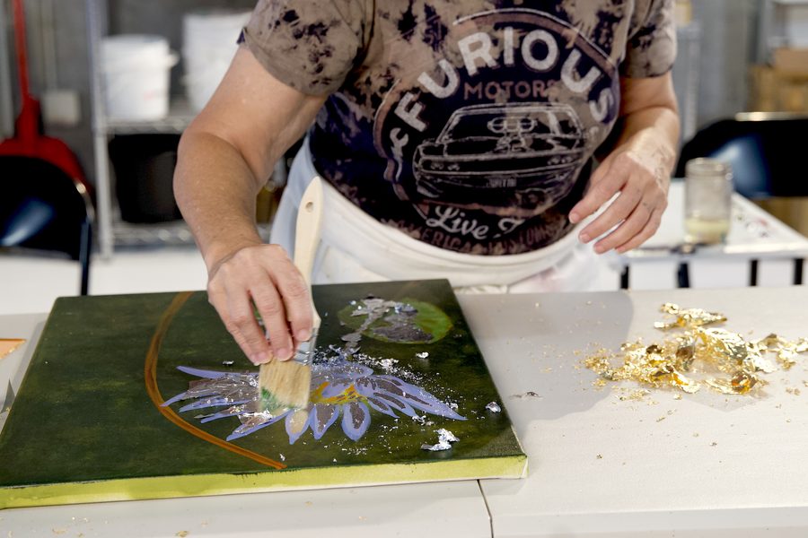 Close-up of hands applying gold leaf to a painting