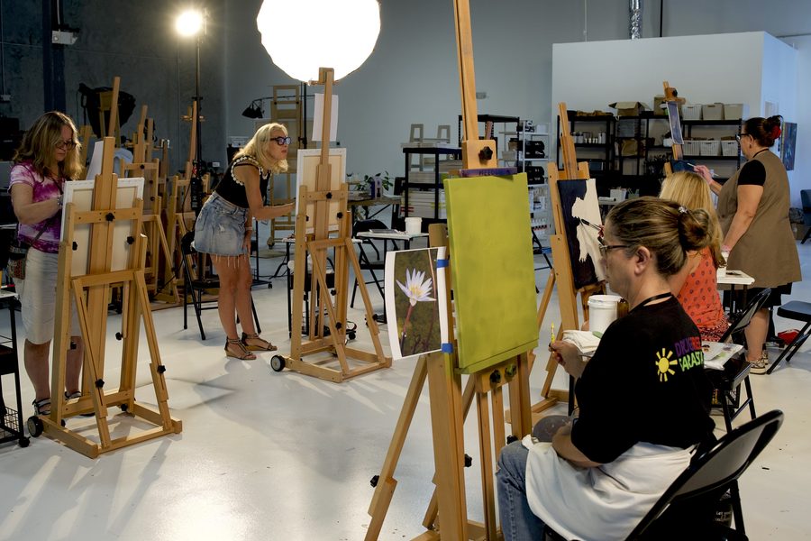 Bright studio full of students painting at rows of easels